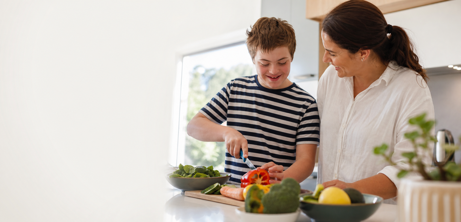 An NDIS child preparing a healthy meal with a support worker at home