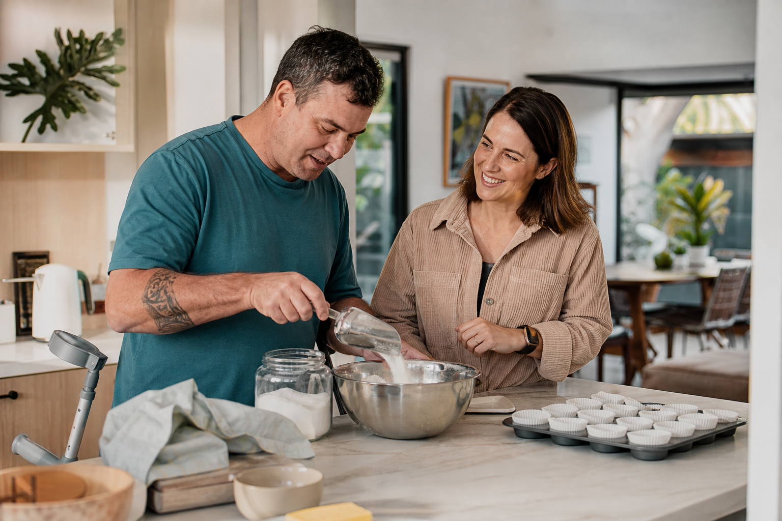An adult NDIS participant baking with a support worker inside a modern home